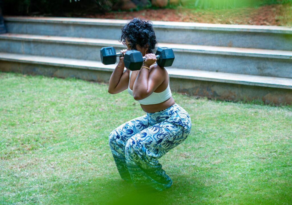 Store manager and personal trainer showing a demonstration of outdoor dumbbell squat exercise | Sculpt by Christlene