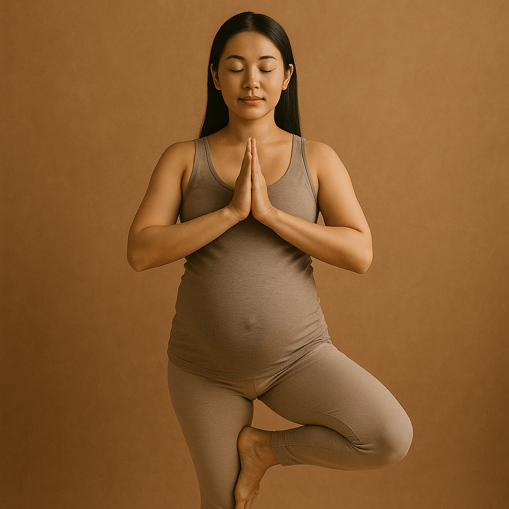 Pregnant woman in a comfortable skin-tight brown shaded outfit peacefully balancing on one leg with hands clasped together in prayer position | Pre & Postnatal Wellness