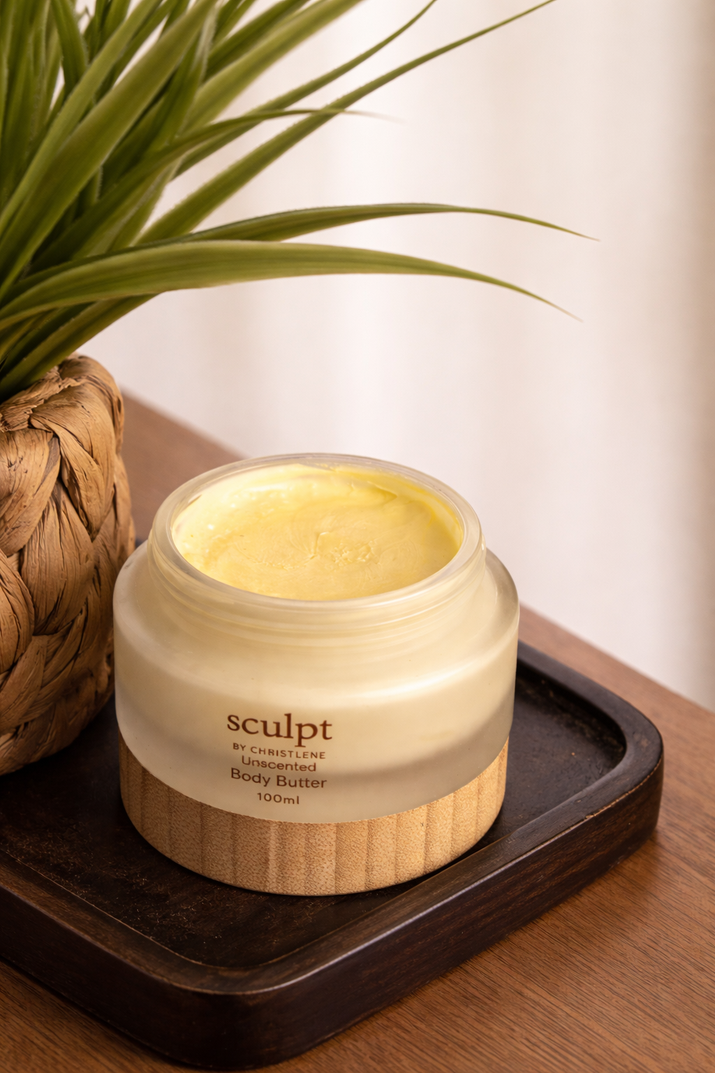 An open jar of unscented body butter placed on a brown surface next to desk plant furniture | available for purchase at Sculpt by Christlene