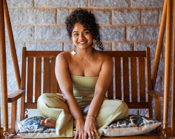 Manager of Sculpt by Christlene sitting on a brown outdoor swing chair while smiling