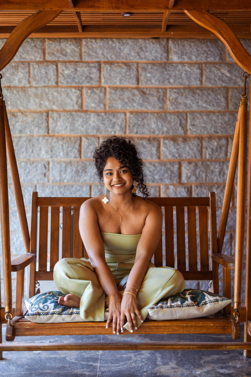 Manager of Sculpt by Christlene sitting on a brown outdoor swing chair while smiling